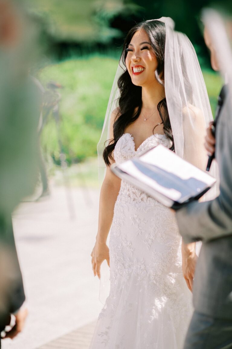 A laughing bride outdoors during her wedding ceremony