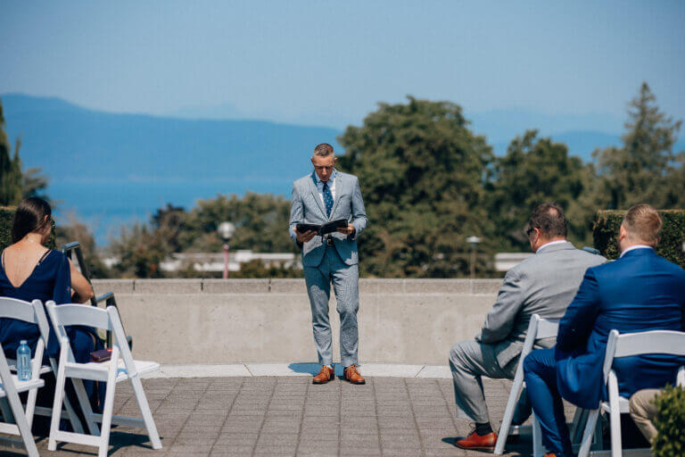 Guests seated at an outdoor terrace ceremony overlooking the water