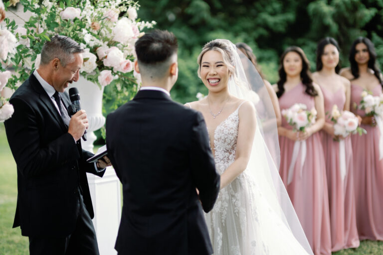 A couple laughing with the officiant at an outdoor ceremony