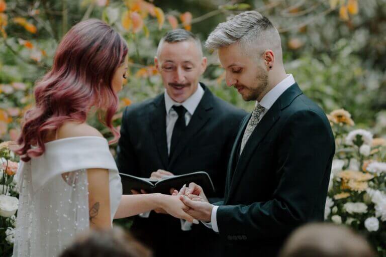 An outdoor forest wedding ceremony with guests watching the couple