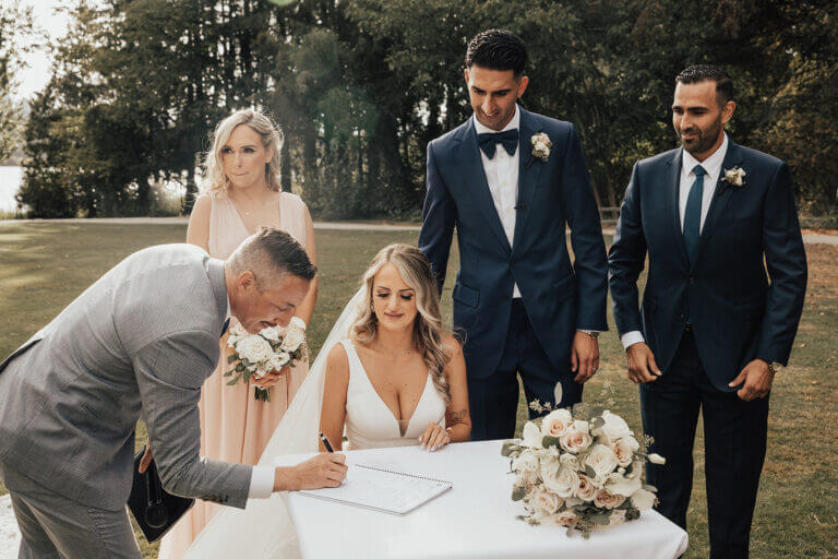 Jonathan Evans leaning in with the couple as they sign the marriage register