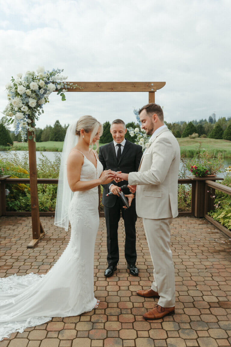 Jonathan Evans standing with a couple beneath a wooden ceremony arch