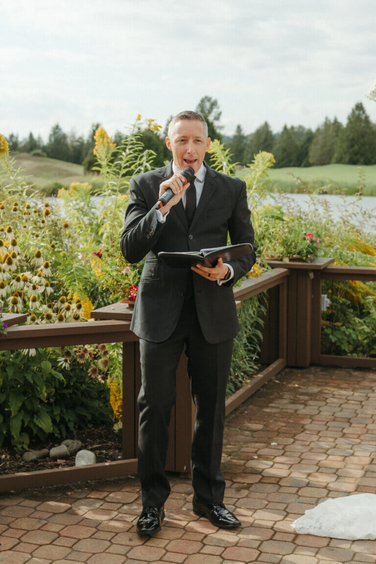 Jonathan Evans speaking into a microphone at an outdoor garden ceremony