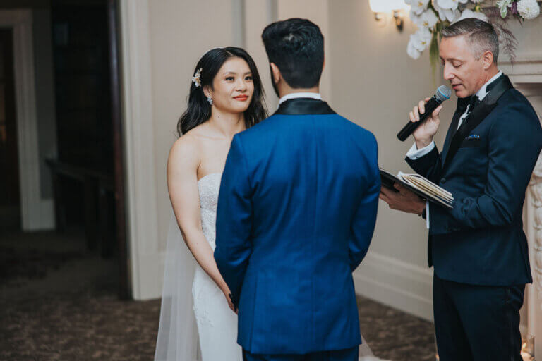 A couple holding hands during their vows, the officiant nearby